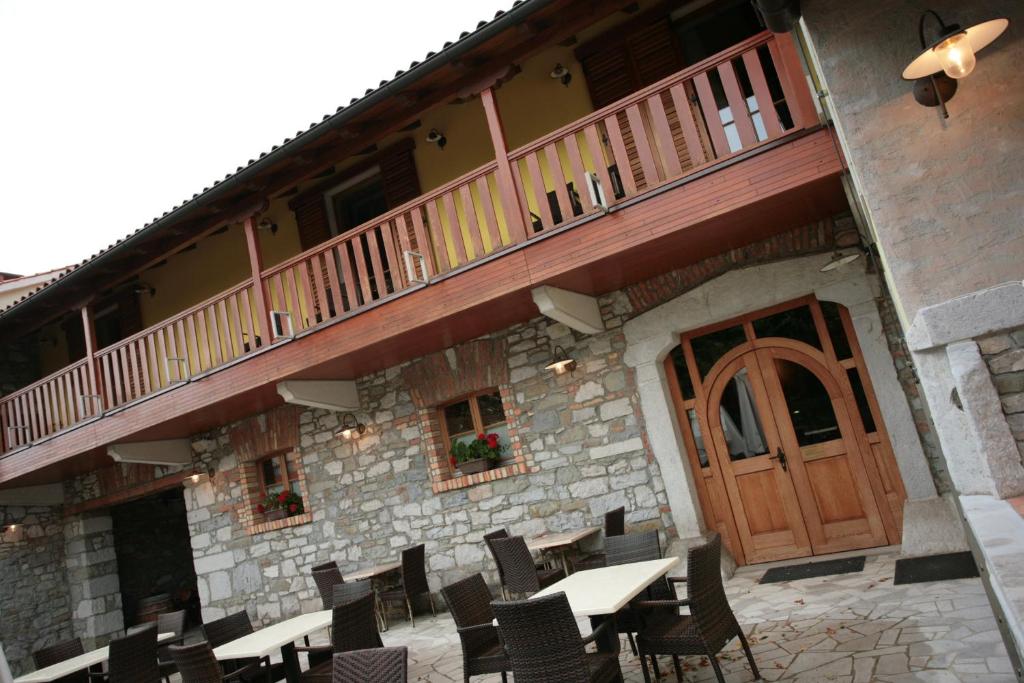 a building with a balcony and tables and chairs at Domačija Linč in Rodik