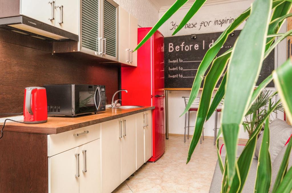 a kitchen with white cabinets and a red wall at Хостел 17 in Kyiv