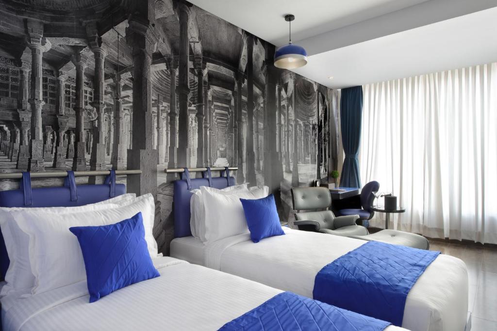 una habitación de hotel con 2 camas y una silla en Regenta Central Antarim Ahmedabad, en Ahmedabad