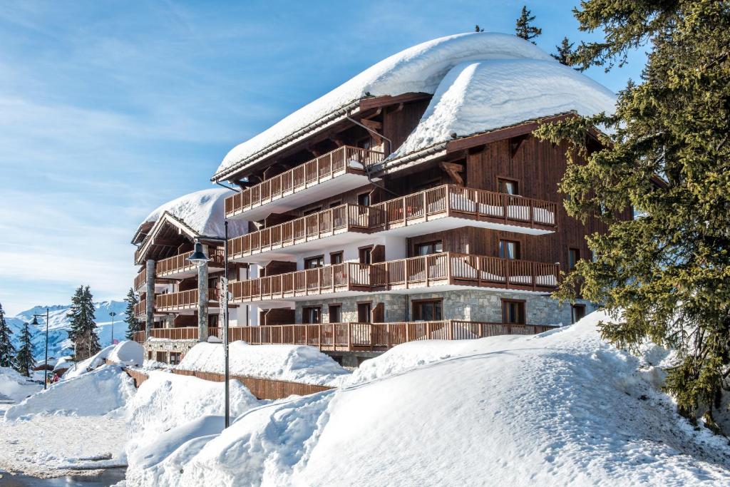 a building with a snow covered roof on top of snow covered ground at CGH Résidences &amp; Spas Chalet Les Marmottons in La Rosière