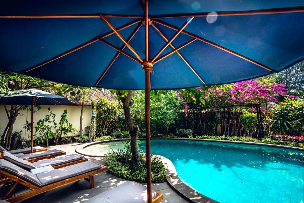 a large blue umbrella next to a swimming pool at Manta Dive Gili Air Resort in Gili Air