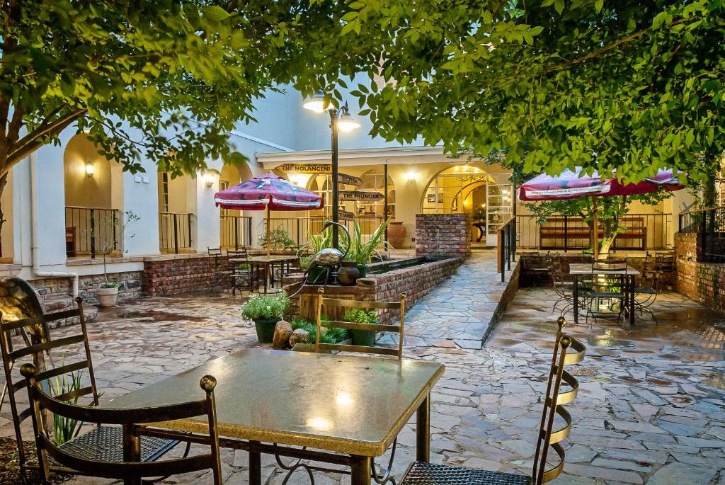 eine Terrasse mit Tischen, Stühlen und Sonnenschirmen in der Unterkunft Nolangeni Hotel in Kokstad