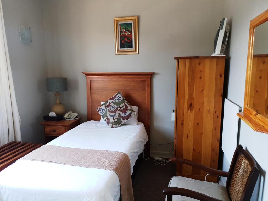 a hotel room with two beds and a chair at Nolangeni Hotel in Kokstad