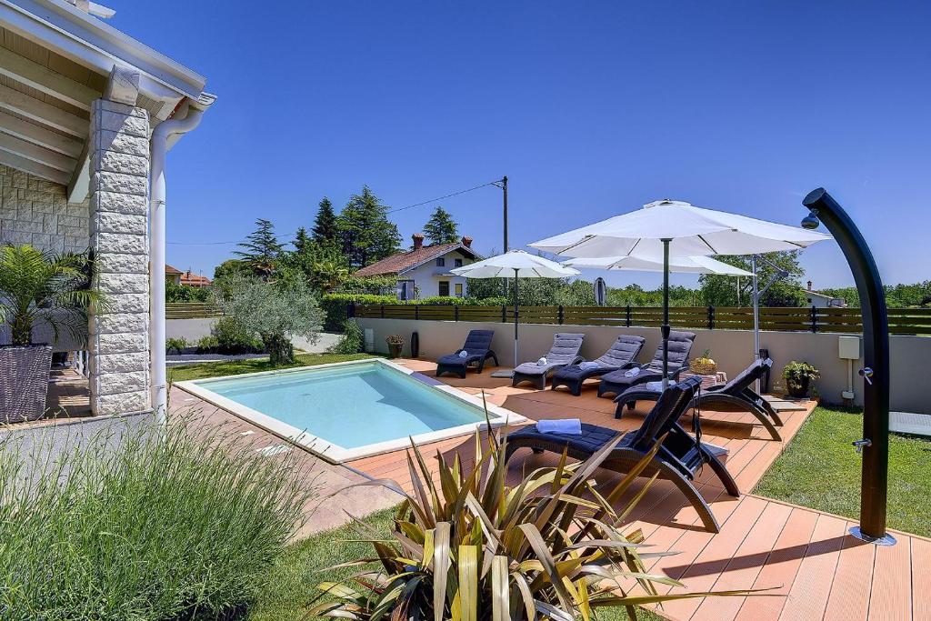 a backyard with a swimming pool and chairs and an umbrella at Villa Laura in Krnica