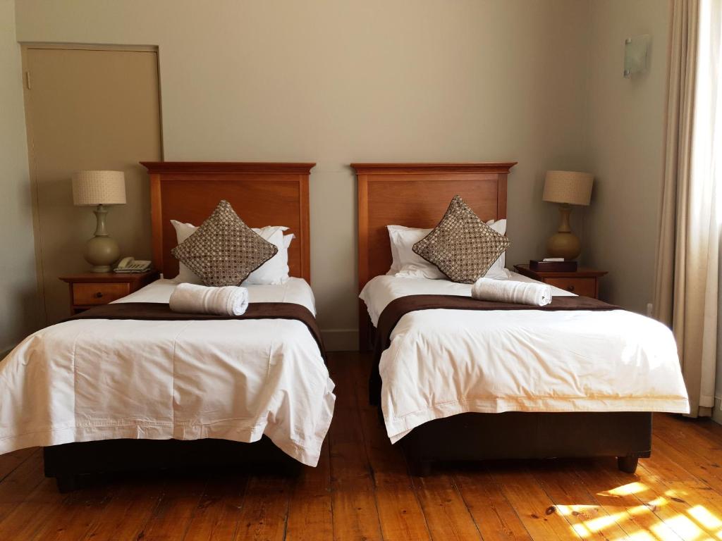 a bedroom with two beds with white sheets and pillows at Nolangeni Hotel in Kokstad