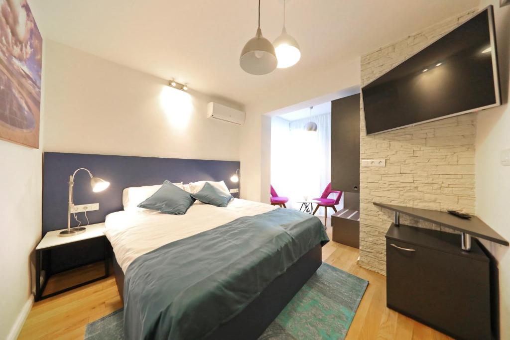 a bedroom with a large bed and a flat screen tv at La Dolce Vita da Zara - Luxury Rooms in Zadar