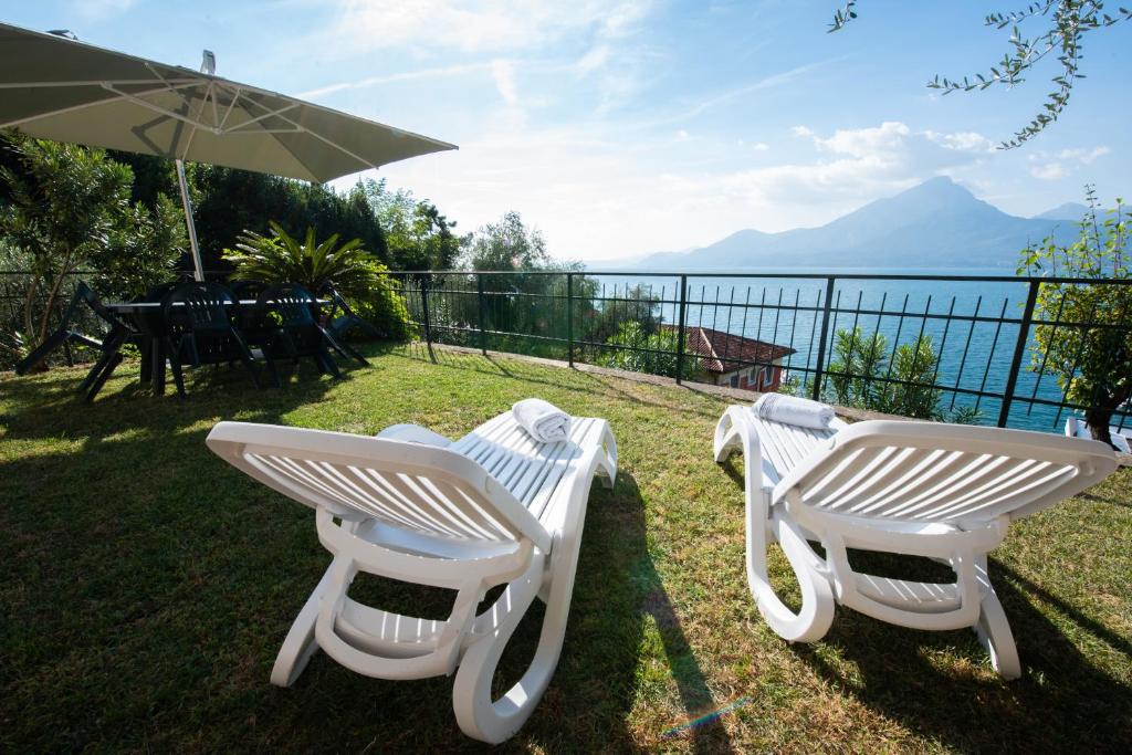 two white chairs and a table and an umbrella at Villa Margherita in Torri del Benaco