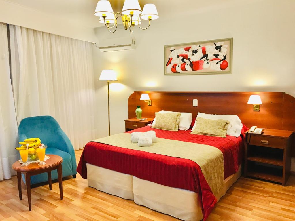a hotel room with a bed and a blue chair at Hostal Del Sol Spa in Termas de Río Hondo