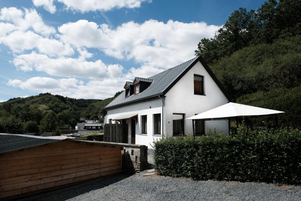 Uma casa branca com um guarda-chuva à frente. em Basic vakantiehuisje op val d'Or em Enscherange