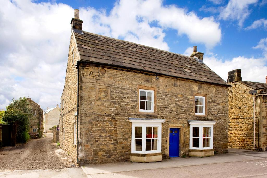 an old brick building with a blue door at Morton House 4brm and Stable Block 3brm in Masham - 2-15 guests in Masham