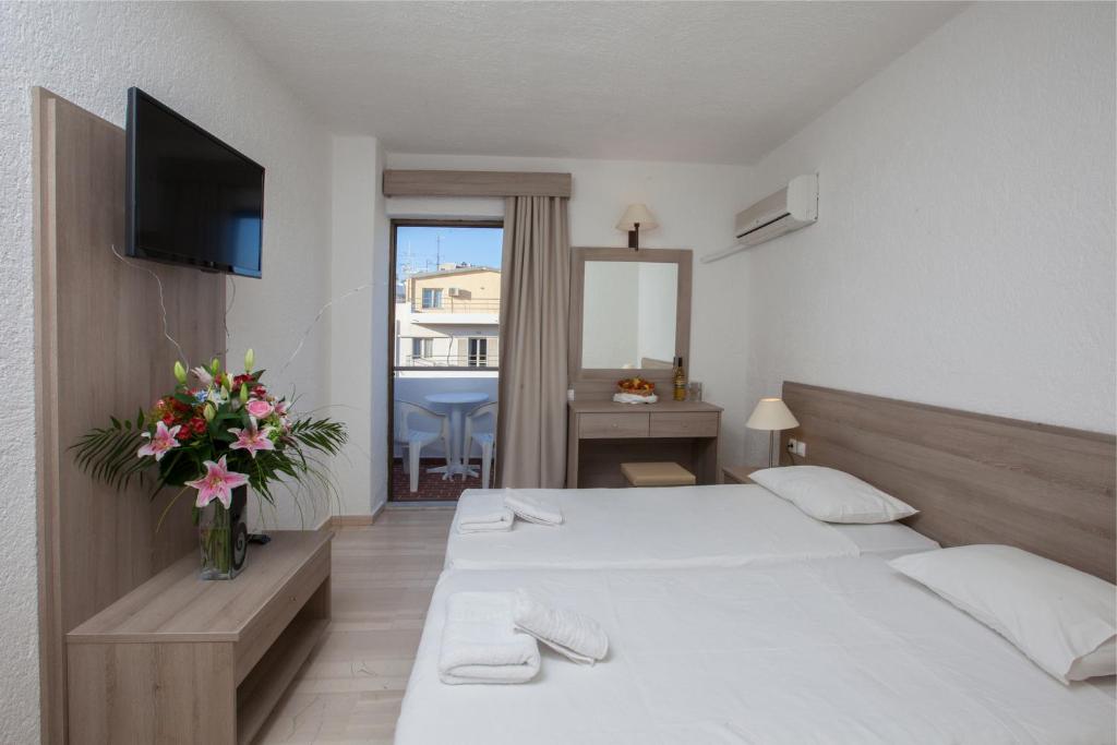 ein Schlafzimmer mit einem Bett und einer Vase aus Blumen in der Unterkunft Apollon Hotel in Agios Nikolaos
