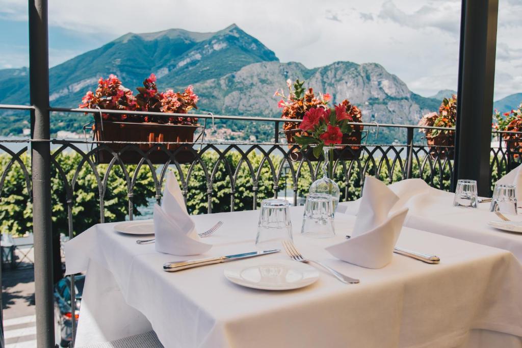 une table avec des nappes blanches sur un balcon avec des montagnes dans l'établissement Hotel Suisse, à Bellagio