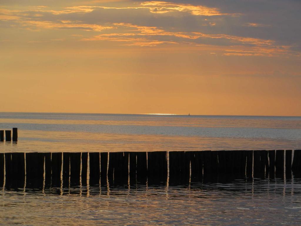 a view of the ocean from a pier at sunset at Exkl_ App_ Buhne_ Kamin_ W_LAN_ 25 in Börgerende-Rethwisch