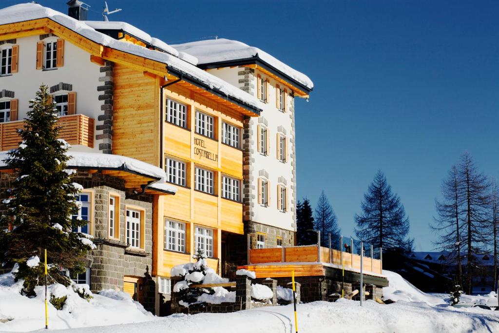 a large building with snow on top of it at Hotel Costabella in Passo San Pellegrino
