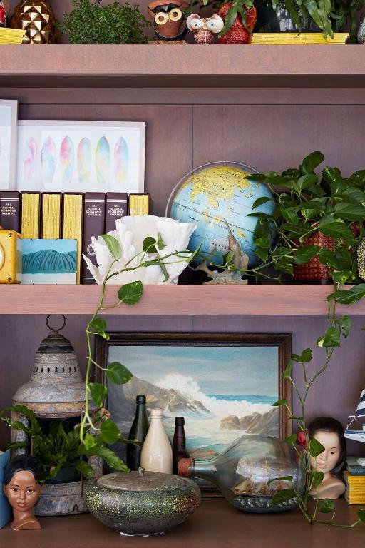 a shelf with a picture and plants and books at The Surfjack Hotel & Swim Club in Honolulu