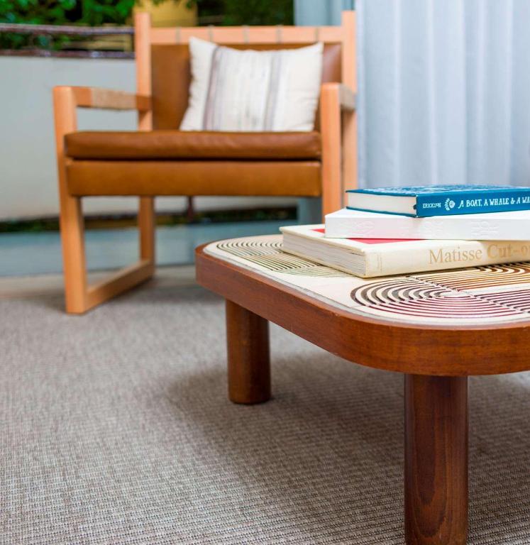 a coffee table with books on it next to a chair at The Surfjack Hotel & Swim Club in Honolulu