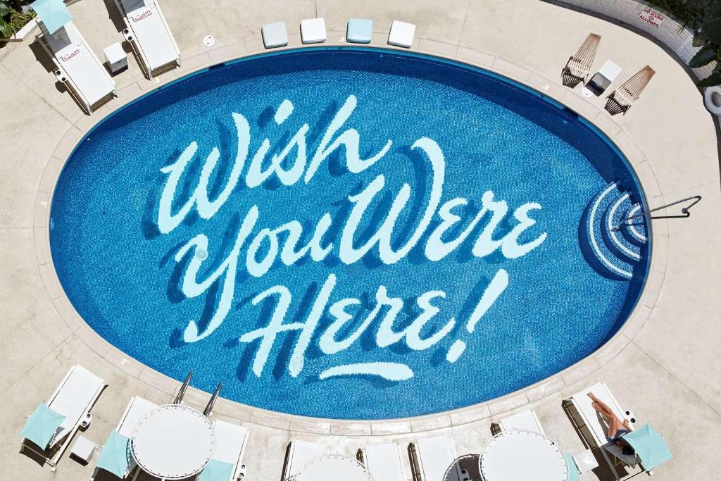 una vista aérea de una piscina con las palabras deseando voluntariamente aquí en The Surfjack Hotel & Swim Club, en Honolulu