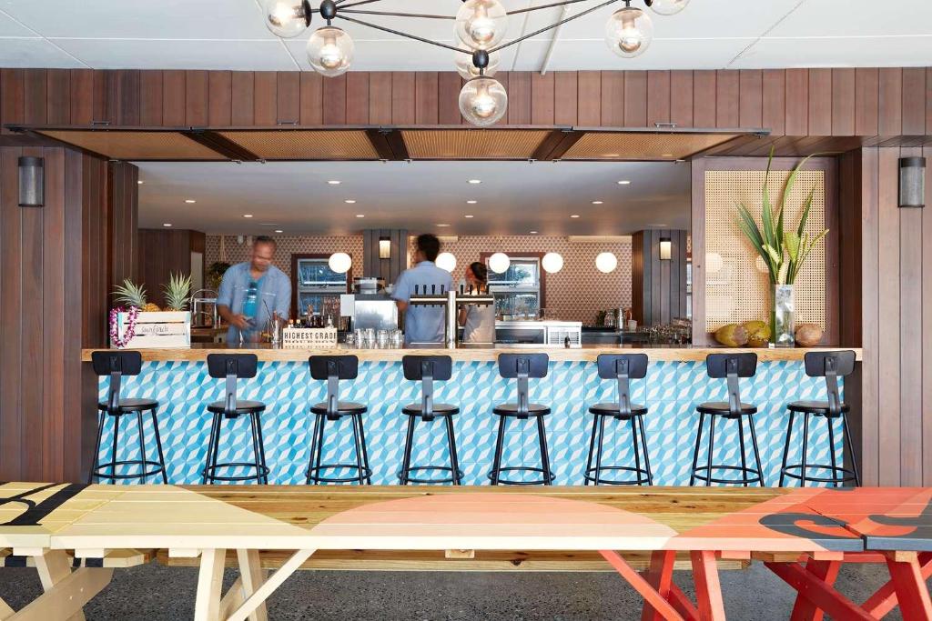 a restaurant with a bar with stools in front of it at The Surfjack Hotel & Swim Club in Honolulu