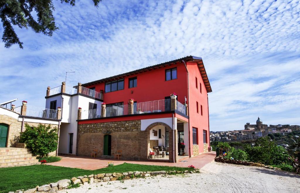 een rood gebouw met een balkon erboven bij La Casa Rossa Country House in Piazza Armerina