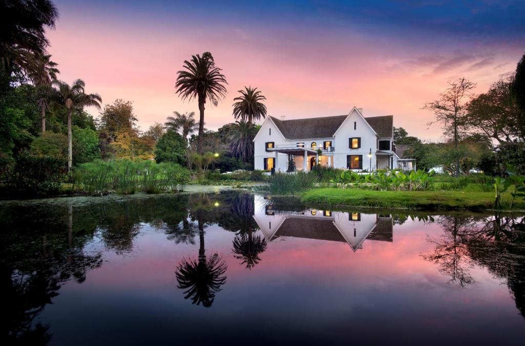 a house with a pond in front of it at The Manor House at Fancourt in George