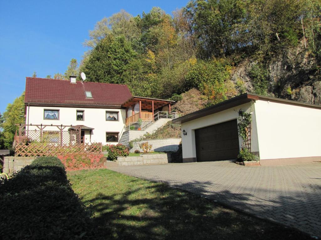 een wit huis met een garage voor een heuvel bij Ferienwohnung Schade in Hohnstein