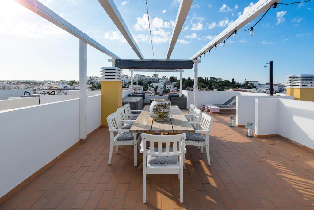 een patio met een tafel en stoelen op een dak bij Casa Kiki in Ferragudo