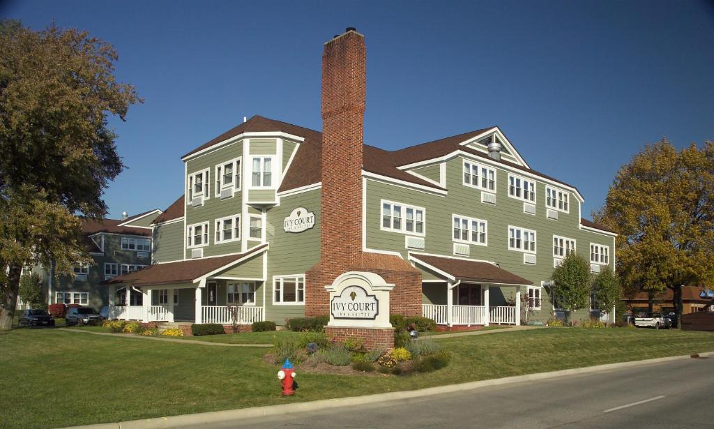 a large house with a brick chimney in front of it at Ivy Court Inn and Suites in South Bend