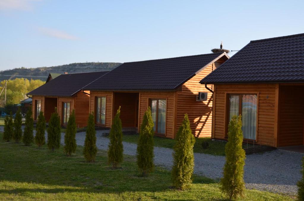 a wooden house with a row of trees in front of it at Hotel Yacht Club Mayak in Dnistrivka