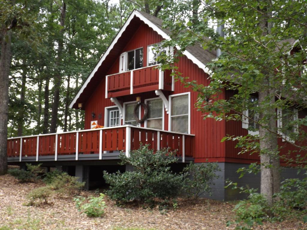een rood huis met een terras in het bos bij Pine Mountain Club Chalets Resort in Pine Mountain