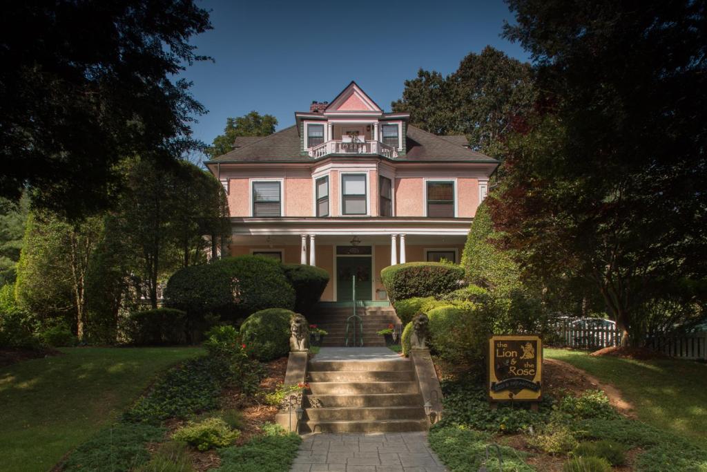 a pink house with a staircase in front of it at The Lion and the Rose Bed and Breakfast in Asheville