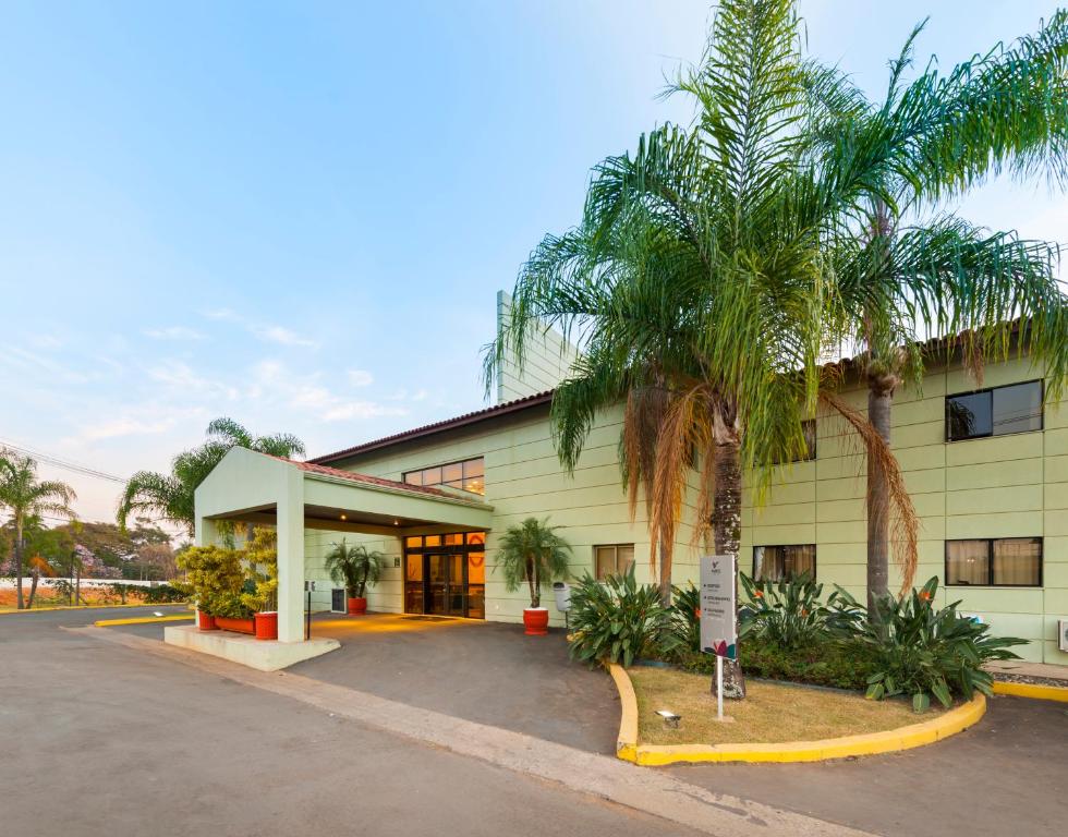 a building with palm trees in front of it at Matiz Jaguariúna in Jaguariúna