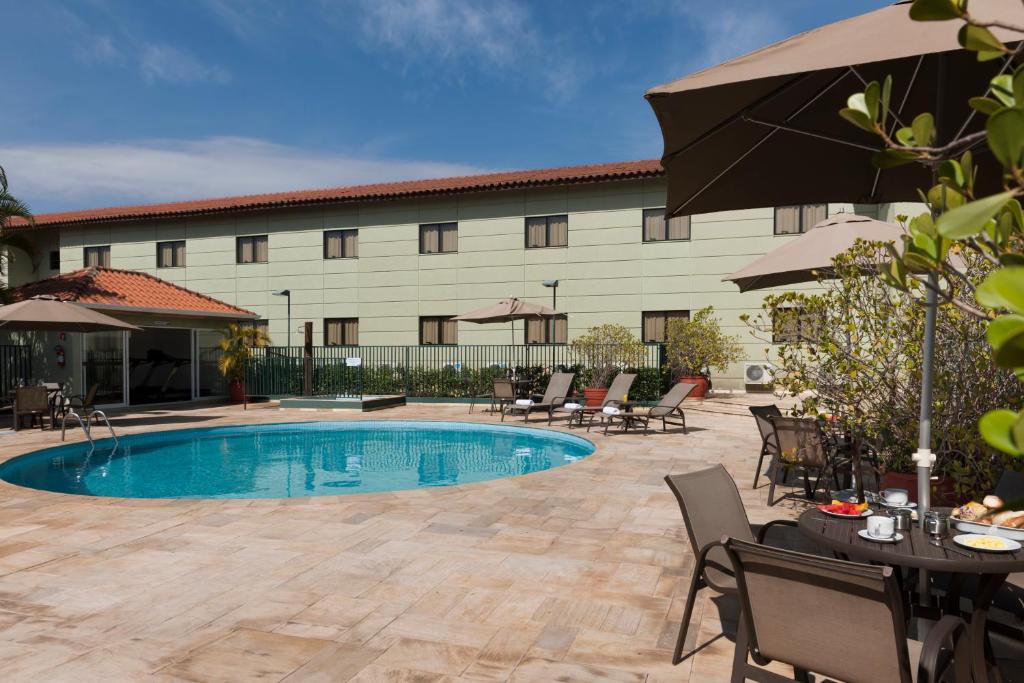 a hotel with a pool and chairs and a building at Matiz Jaguariúna in Jaguariúna