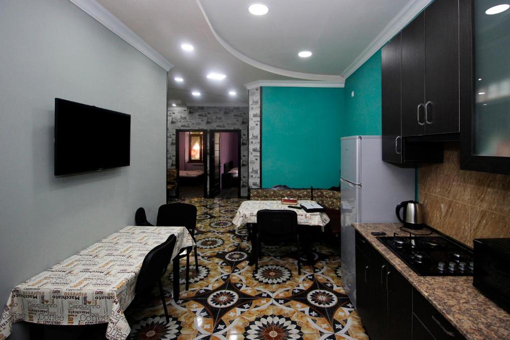 a room with two tables and a kitchen with green walls at Hotel Victoria in Yerevan
