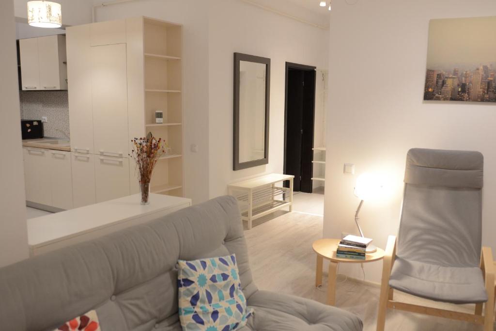 een witte woonkamer met een bank en een stoel bij Cozy Apartments - City Center in Iaşi