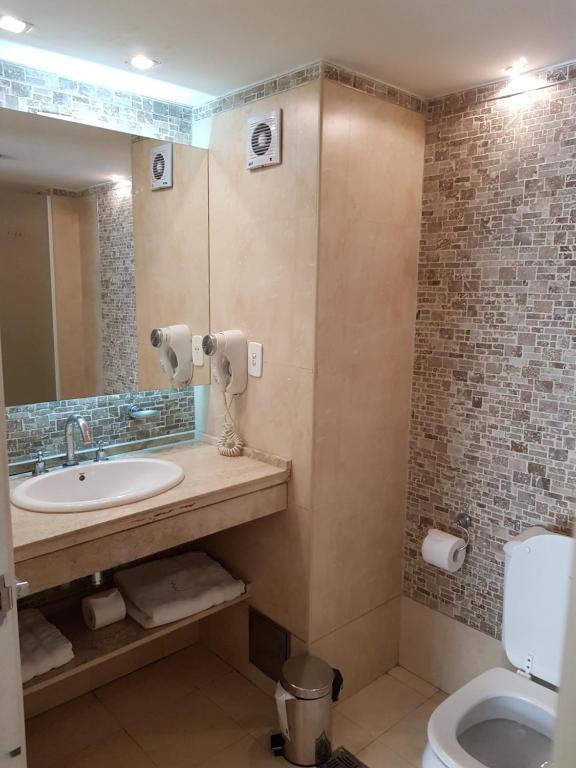 uma casa de banho com um lavatório, um WC e um espelho. em Villaggio Hotel Boutique em Mendoza