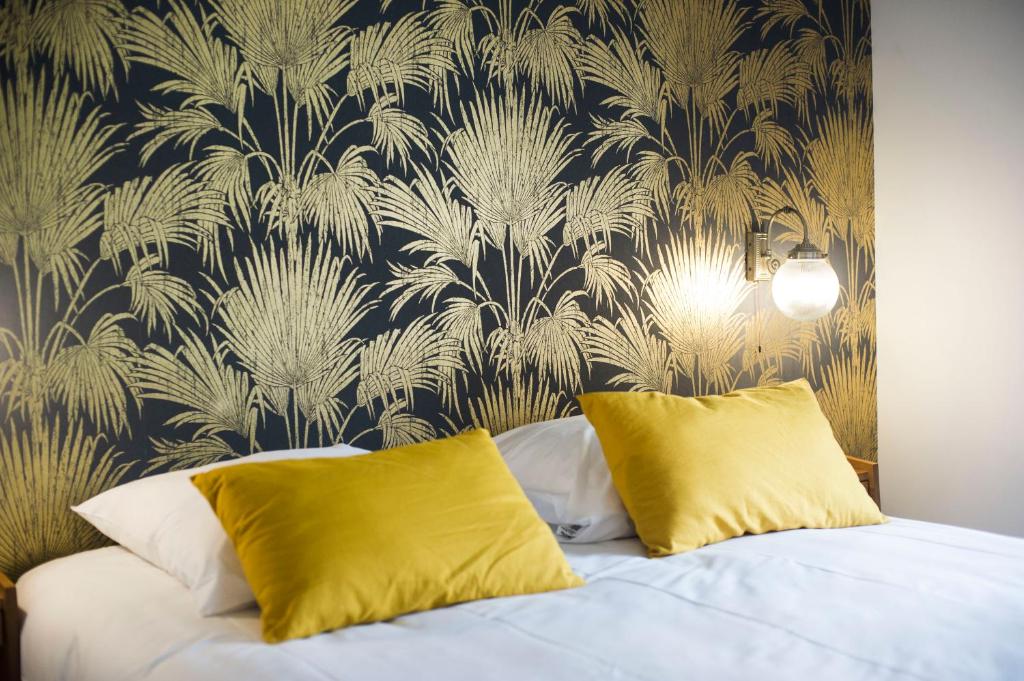 a bedroom with a bed with yellow pillows and a wallpaper at Georges Hostel & Café in Sète