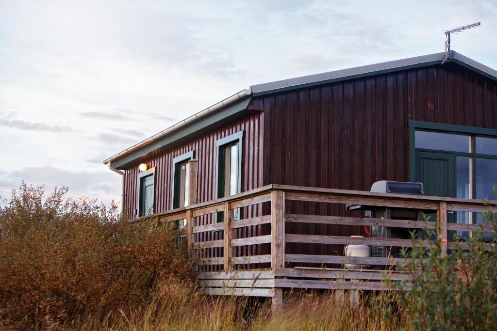 ein Holzhaus mit Fenstern auf einem Feld in der Unterkunft Hestaland Riverside Cottage in Staðarhús