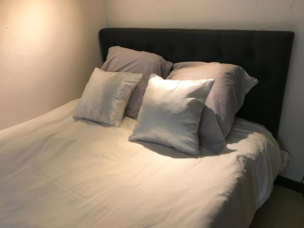 a bed with four pillows on top of it at Studio 2 pers en vieille ville parking gratuit - by La Source d'OrFée in Boulogne-sur-Mer