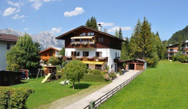 ein großes Haus auf einem grünen Feld mit einem Zaun in der Unterkunft Appartment Haus Birgit in Seefeld in Tirol