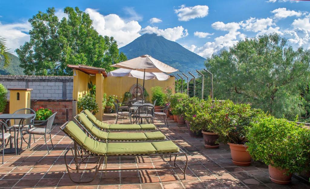 een patio met stoelen, een parasol en een berg bij Hotel Las Camelias Inn by AHS in Antigua Guatemala