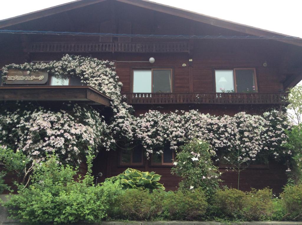 Una casa con flores blancas a un lado. en Yamagata Zao Pension Aplon Stage, en Kaminoyama
