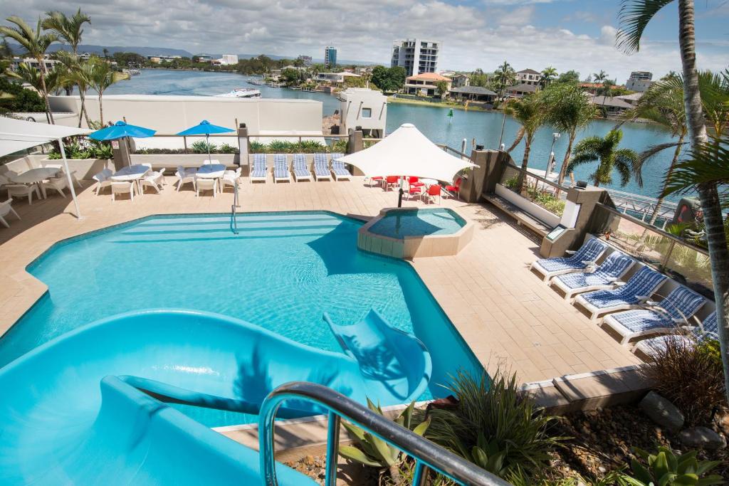 una piscina en el complejo con sillas y sombrillas en Tiki Hotel Apartments Surfers Paradise en Gold Coast