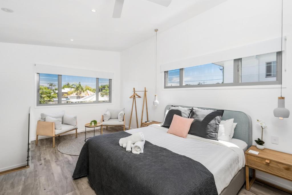 a bedroom with a large bed and two windows at Aloha Byron Bay in Byron Bay