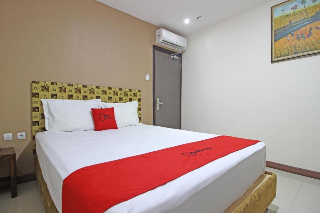 1 dormitorio con 1 cama grande con manta roja en RedDoorz near UNS Solo, en Solo