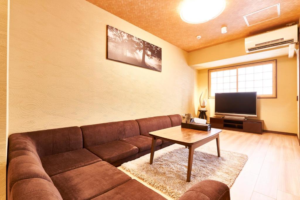 a living room with a brown couch and a table at Miyazakiya Plus in Kyoto