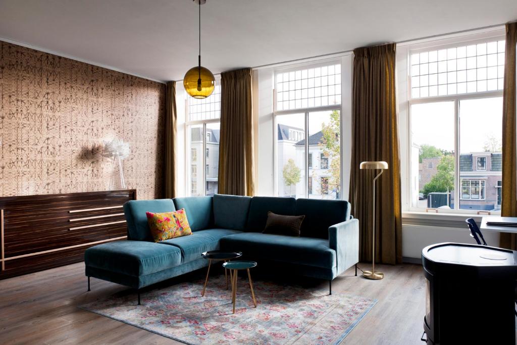 a living room with a blue couch and some windows at Rooftop 52, City-Apartment in Assen