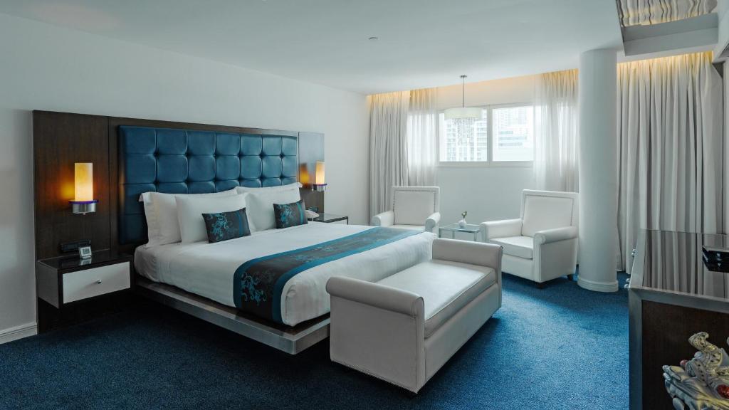 a hotel room with a large bed and a chair at Dream Hotel Bangkok in Bangkok