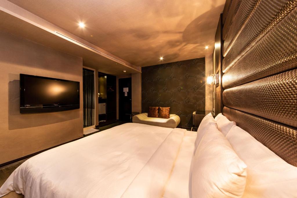 a bedroom with a large bed and a television at The Riverside Hotel Fashion in Kaohsiung