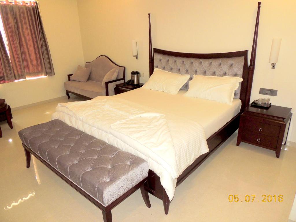 a bedroom with a large bed and a chair at Hotel Darshan in Visnagar