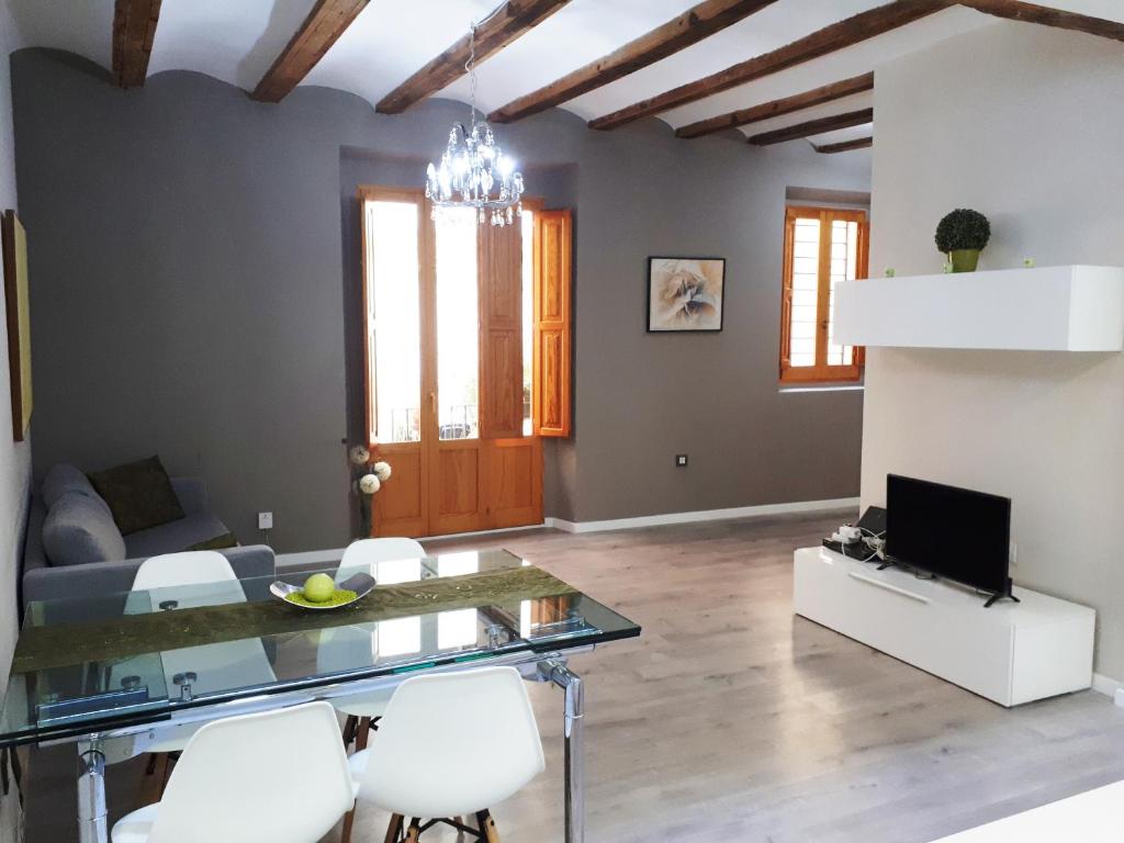 バレンシアにあるAmplio apartamento en centro históricoのリビングルーム(ガラステーブル、白い椅子付)